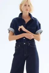 Pantalón de jean azul oscuro de corte holgado, con tiro alto, cinco bolsillos y cierre con botón.