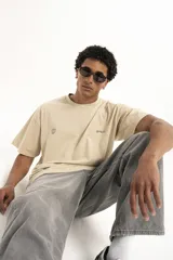 Remera color arena de corte holgado con cuello redondo y manga corta. Presenta un pequeño estampado en el frente.