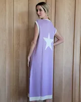 Vestido midi lila de punto con cuello redondo y ribete en color crema. Presenta una estrella blanca en la espalda y aberturas laterales en el ruedo.