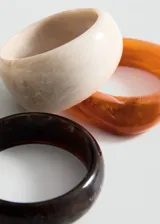 Pack de tres pulseras rígidas de acrílico en color marrón, naranja y beige.