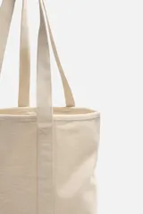 Bolso tipo shopper color crudo, fabricado en tejido de algodón. Tiene doble asa de hombro y un bolsillo interior plano.
