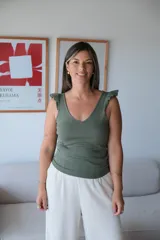 Musculosa de tejido de punto color verde musgo, con escote en V y volados en los hombros. Presenta un borde inferior acanalado.