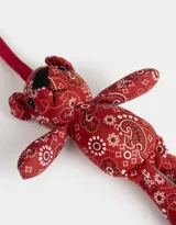 Llavero con forma de oso de peluche rojo con estampado paisley y cinta de agarre roja.