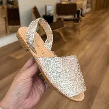 Sandalias tipo avarcas plateadas con acabado brillante y tira trasera.