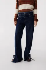 Pantalón de jean azul oscuro de corte recto, con cintura alta con cinturón del mismo material y detalle de flecos en la cintura y en los tobillos.