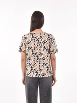 Remera de manga corta con estampado abstracto en tonos beige, negro y blanco.