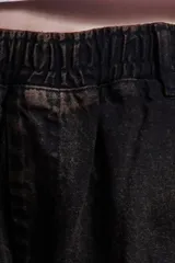 Pantalón unisex color óxido confeccionado en denim de algodón con cintura elástica, tiro alto, corte holgado, pierna ancha, largo estándar, bolsillos laterales y un bolsillo trasero.