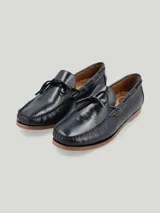 Mocasín náutico de cuero azul marino con suela de goma color marrón claro y cordones de cuero.