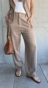 Pantalón de vestir color tostado con finas rayas verticales blancas, de corte palazzo y tiro alto.