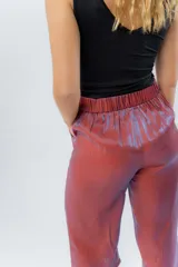 Pantalón de lino con acabado metalizado tornasolado, que refleja tonos entre rosa y lila según la luz. De corte recto y largo ¾, tiene cintura con elástico en la espalda que aporta comodidad y un calce relajado.