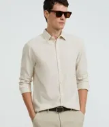 Camisa celeste de lino con cuello camisero, abotonadura frontal y mangas largas.