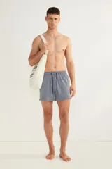 Short de baño azul marino con rayas verticales blancas, cintura elástica con cordón ajustable, bolsillos laterales y bolsillo trasero con cierre autoadherente.
