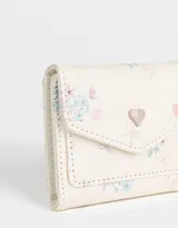 Billetera pequeña de cuerina color crema con estampado floral en tonos rosa y celeste. Tiene solapa con broche a presión en forma de corazón.