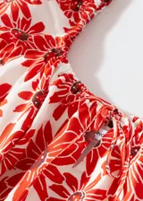 Vestido corto evasé de algodón con estampado de margaritas rojas, cuello cuadrado con lazo y mangas cortas abullonadas. Incluye forro interior y espalda abierta.