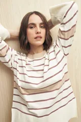 Sweater de rayas horizontales color crudo y marrón, con cuello redondo a contratono color beige, tajos laterales y mangas largas con puño ancho.