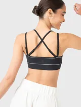 Top deportivo negro con breteles finos ajustables que se cruzan en la espalda, con sutil fruncido en el centro del busto y ribete blanco.