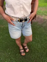 Cinto de cuero con forro de cuero, estampado animal print de vaca en blanco y negro, con hebilla metálica rectangular color bronce y broche suizo.