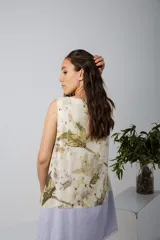 Vestido corto sin mangas, con estampado de hojas en tonos beige y verde, y falda color lila con detalle de flecos en el ruedo.