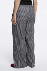 Pantalón de tela rayada vertical en tonos azul y blanco, con cintura elástica y cordón ajustable.