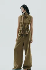 Pantalón palazzo color verde oliva de tejido fluido, tiro medio, cintura elástica ajustable con cordones y bolsillos laterales.