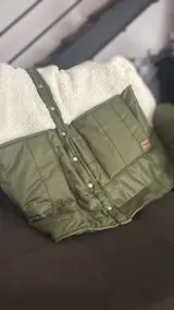Campera con parte superior de corderito color blanco y parte inferior capitoneada a rayas color verde militar. Tiene botones a presión y corte oversize.