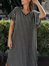 Vestido largo de tejido a rayas horizontales en tonos beige y blanco, con escote en V y mangas cortas tipo murciélago. Presenta tajos laterales en el ruedo.