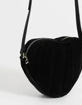 Bandolera negra en forma de corazón, confeccionada en cuerina acolchada con pespuntes verticales. Tiene correa larga regulable y cierre superior.