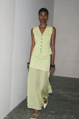 Falda midi color crudo, de tiro alto con cintura elástica y detalle de tejido combinado plisado y semitransparente. Cierre lateral con cremallera oculta en costura.