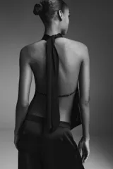 Top sin mangas color blanco, con cuello halter drapeado y bajo asimétrico con caída.