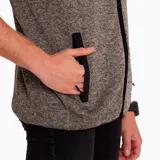 Chaleco de polar color gris jaspeado con cierre frontal, cuello alto, bolsillo en el pecho con cierre y bolsillos laterales con interior de polar.