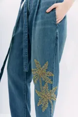 Pantalón de jean tiro alto con corte paper bag, lazo a tono en la cintura y bordado con lentejuelas y piedras en el lateral.