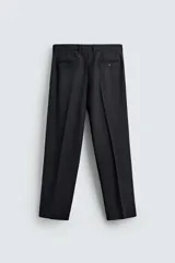 Pantalón de vestir negro de corte relaxed fit confeccionado en tejido con lana. Cuenta con bolsillos frontales y traseros de doble vivo con botón. Cierre frontal con cremallera y botón.