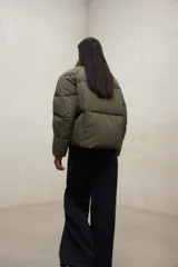 Campera acolchada negra, estilo puffer, con cuello alto y cierre frontal. Diseño oversize.