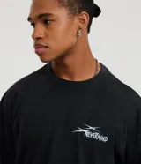 Remera negra de algodón con efecto desteñido (stone wash), corte boxy y manga corta. Estampa grande en la espalda con cinco calaveras amarillas y texto en blanco que dice "SAVAGE SQUAD" y debajo "WE WERE NEVER QUIET".