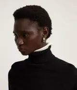 Blusa de punto color blanco, con cuello alto, manga larga y diseño liso.