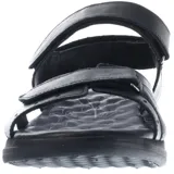 Sandalias negras de mujer, estilo casual, con tiras ajustables mediante velcro en el empeine y tobillo. Presentan una suela gruesa y ergonómica con plantilla contorneada. Se observa un logo grabado en la tira del tobillo.