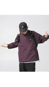 Chaqueta tipo anorak impermeable de color negro, con cuello alto y cierre parcial frontal. Presenta un pequeño logo en el pecho y ajuste regulable en la cintura para un calce más holgado o ceñido.