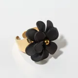 Anillo dorado con aplique de flor negra con centro dorado.