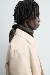 Sobrecamisa color beige de algodón con estructura canvas, corte relaxed fit, cuello solapa, manga larga con puño abotonado, bolsillos de plastrón frontales y cierre frontal con botones.