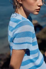 Top de punto celeste con rayas horizontales en azul. Tiene cuello redondo y mangas cortas.