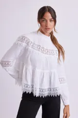 Blusa blanca de manga larga con cuello alto y detalles de encaje.
