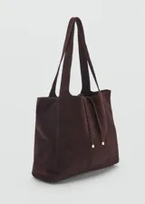 Bolso shopper de gamuza marrón chocolate, con doble asa corta y asa de hombro. Tiene cierre de cremallera y lazo ajustable.