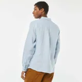 Camisa celeste de lino, de corte recto, con cuello clásico y mangas largas con puños abotonados.