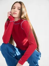 Polera negra de tela rib con cuello alto y mangas largas. Presenta pespuntes rojos en cuello, hombros y puños.
