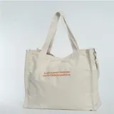 Bolso tipo shopper de tela color crema con asas cortas y correa larga desmontable. Estampado de un ave fénix color naranja.