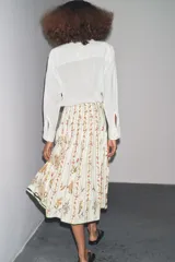 Falda midi de tiro medio confeccionada en hilatura de algodón. Tejido con tablas y estampado floral. Bajo acabado en vivo a contraste. Cierre lateral con cremallera oculta en costura.