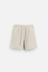 Bermuda regular fit negra confeccionada en tejido de lino. Cintura elástica ajustable con cordón y pliegues frontales. Bolsillos frontales y detalle de bolsillos traseros de plastrón.