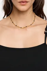 Collar dorado con cadena de eslabones y pequeños dijes de corazones negros.