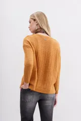 Sweater color mostaza de tejido de punto con detalle de lentejuelas integradas al hilado, calce holgado y mangas largas.