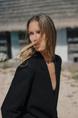Blazer negro de lino con cuello solapa y escote pico. Manga larga con hombreras y puños con vuelta estampada a rayas. Bolsillos con solapa en el delantero, forro interior y cierre frontal con botón.